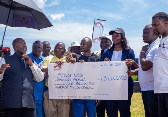 Fred Bwino Kyakulaga the State Minister of Agriculture, Animal Industry and Fisheries presents a dummy cheque of UGX 1.2b with Equity Bank’s Director of Public Sector And Social Investment Catherine P