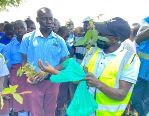 Denis Emmanuel Oweka- ECOTRUST's regional project coordinator training students on how to use aqua soil during the tree planting session 01